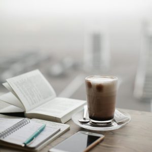 pexels-photo-1684151-1684151 A warm coffee sits beside a notebook and smartphone on a foggy day.