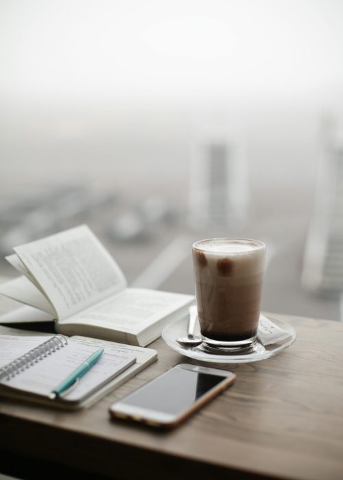 pexels-photo-1684151-1684151 A warm coffee sits beside a notebook and smartphone on a foggy day.