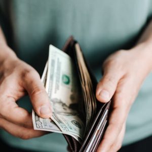 pexels-photo-4386433-4386433-1 Close-up of hands holding a wallet with cash, depicting financial management.